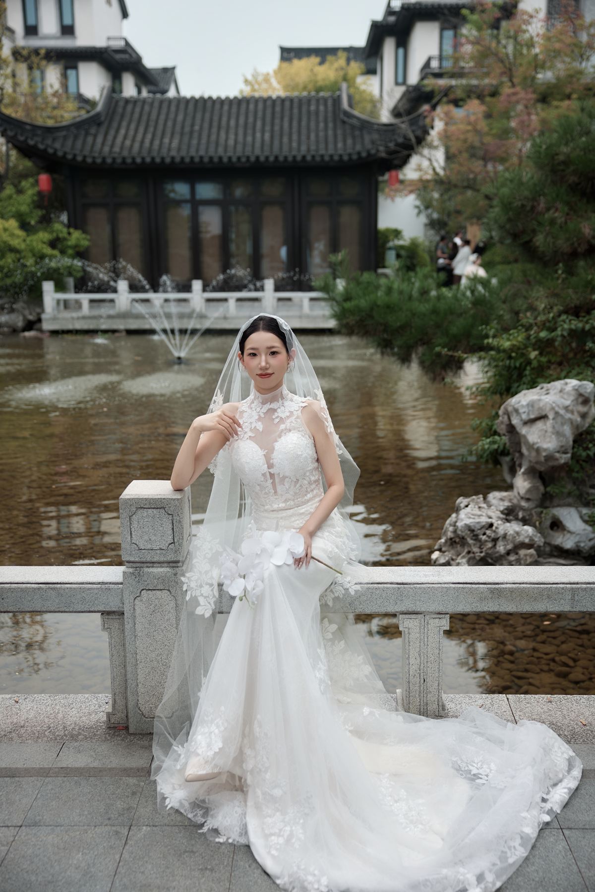 韦晶晶坐在池畔石栏上的婚纱照